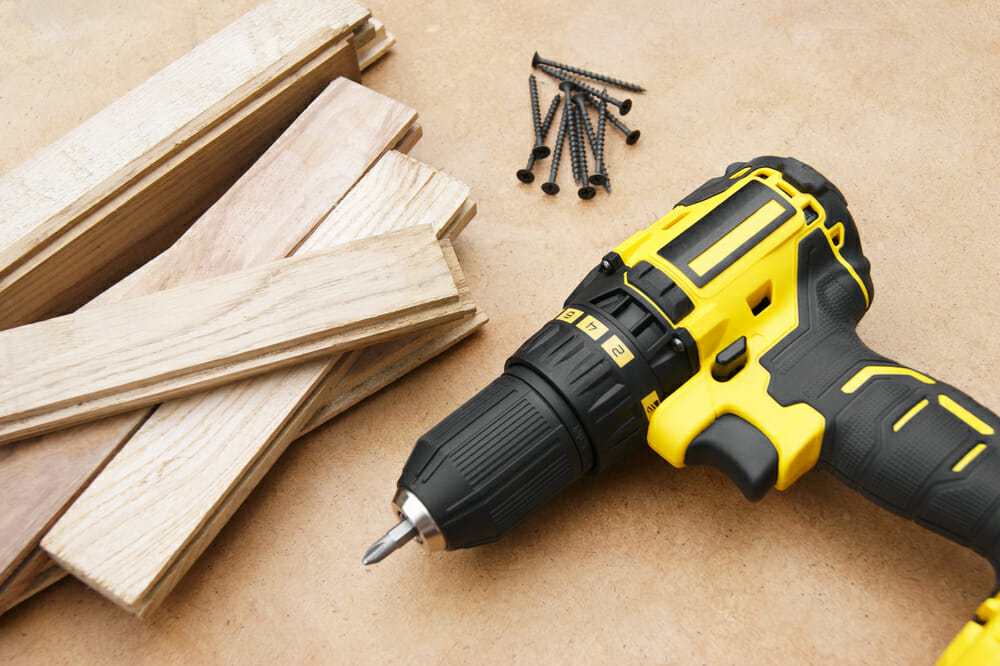 The yellow-black screwdriver on wood background, screws.